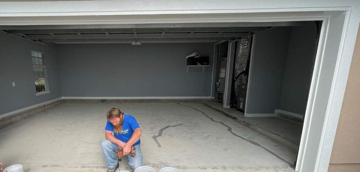 The Palencia garage before coating: bare, cracked concrete, with the crew mixing at the door, St. Augustine FL