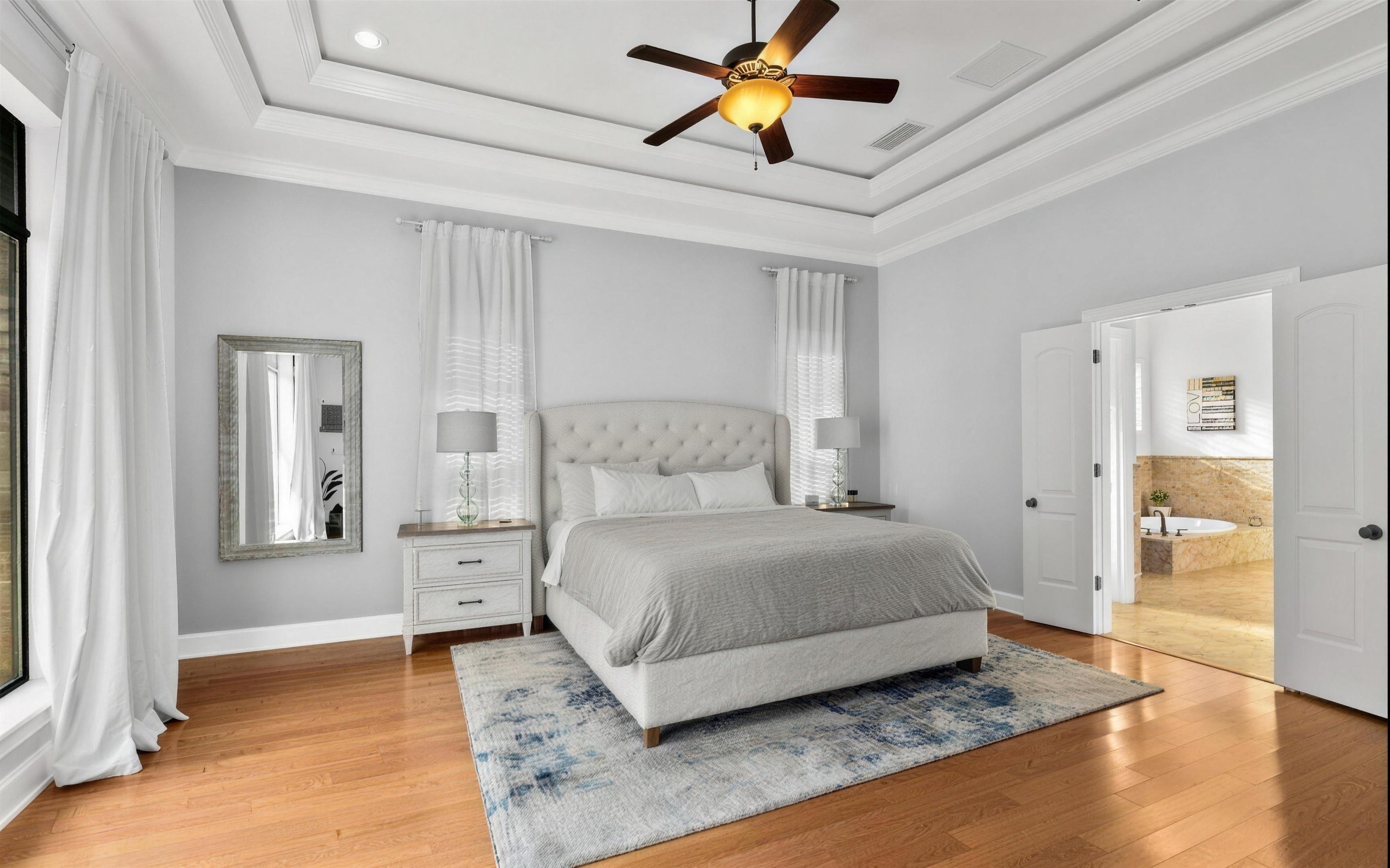 Primary suite in a Jacksonville home after interior painting, soft grey walls, white trim and a tray ceiling