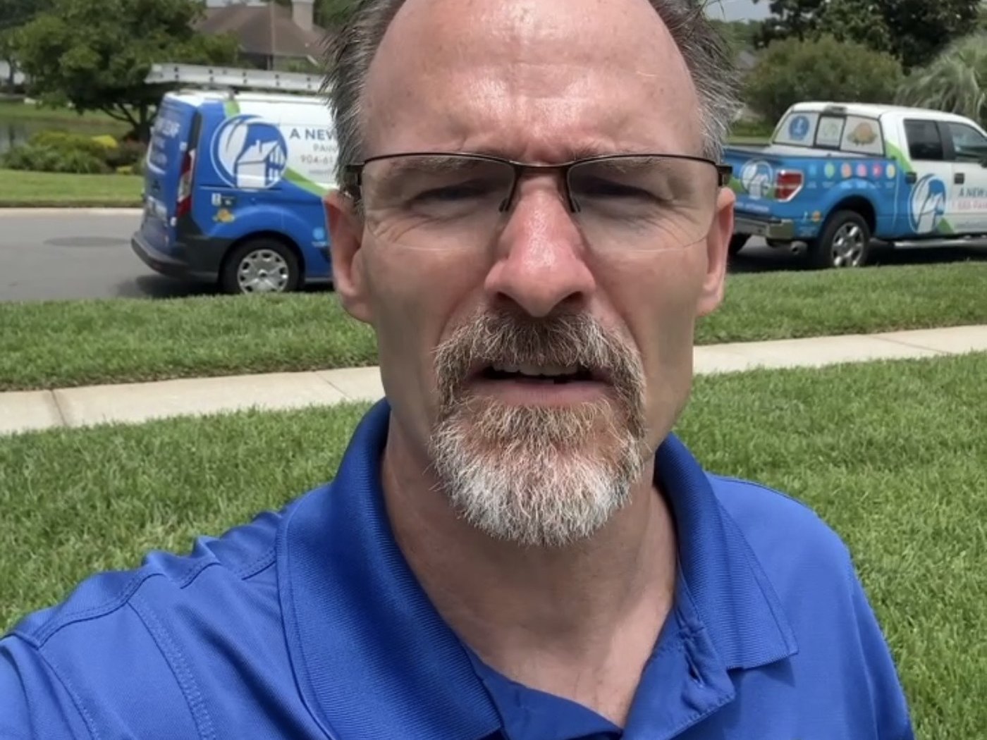 Thomas Drake on a customer's lawn with two A New Leaf trucks behind him