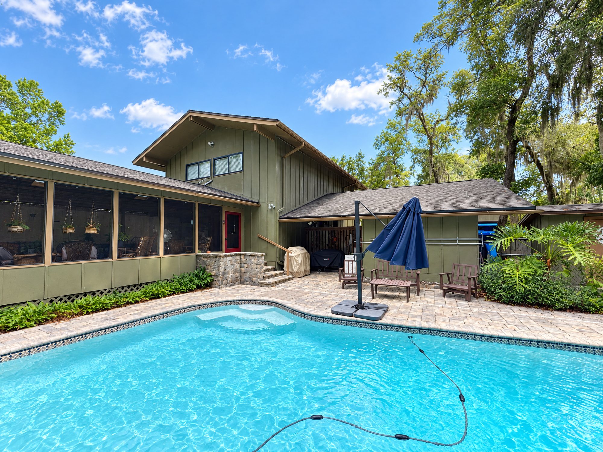 Before: an Orange Park home seen from the pool deck, with olive board-and-batten siding, a screened porch and brown fascia