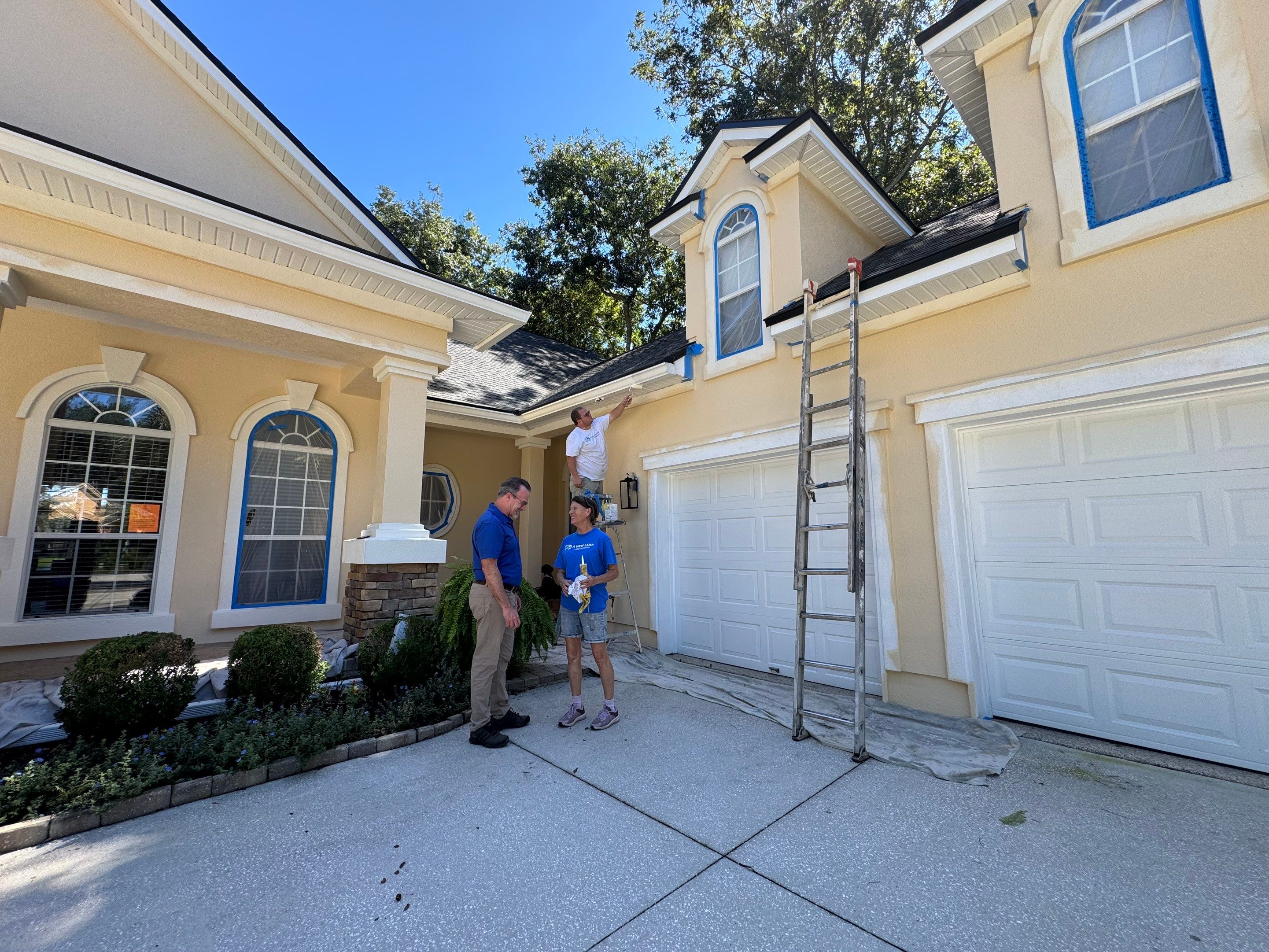 Professional painters completing exterior prep on a synthetic stucco home in Queens Harbor