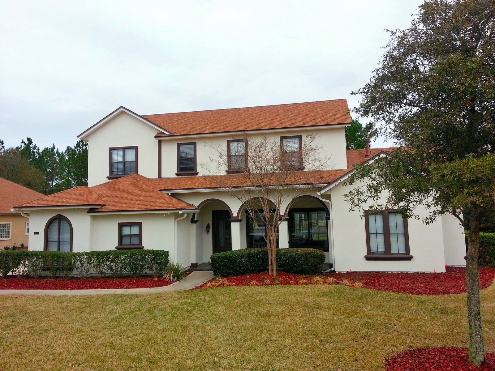 White stucco home with brown trim and tile roof after exterior repaint in OakLeaf Plantation