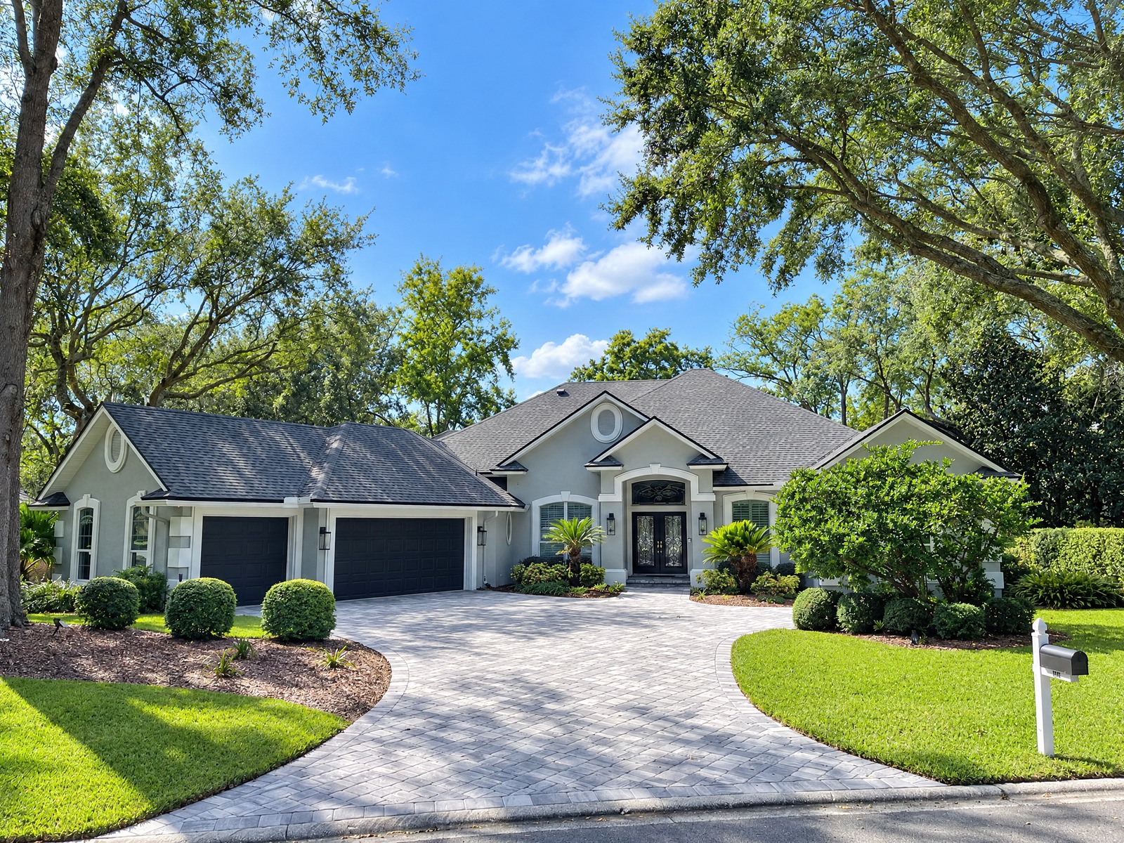 Grey stucco exterior with black garage doors after repaint in Queens Harbor, Jacksonville FL