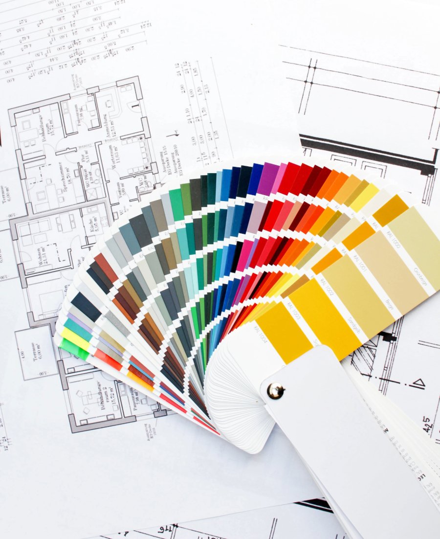 A paint color fan deck open over a set of house plans