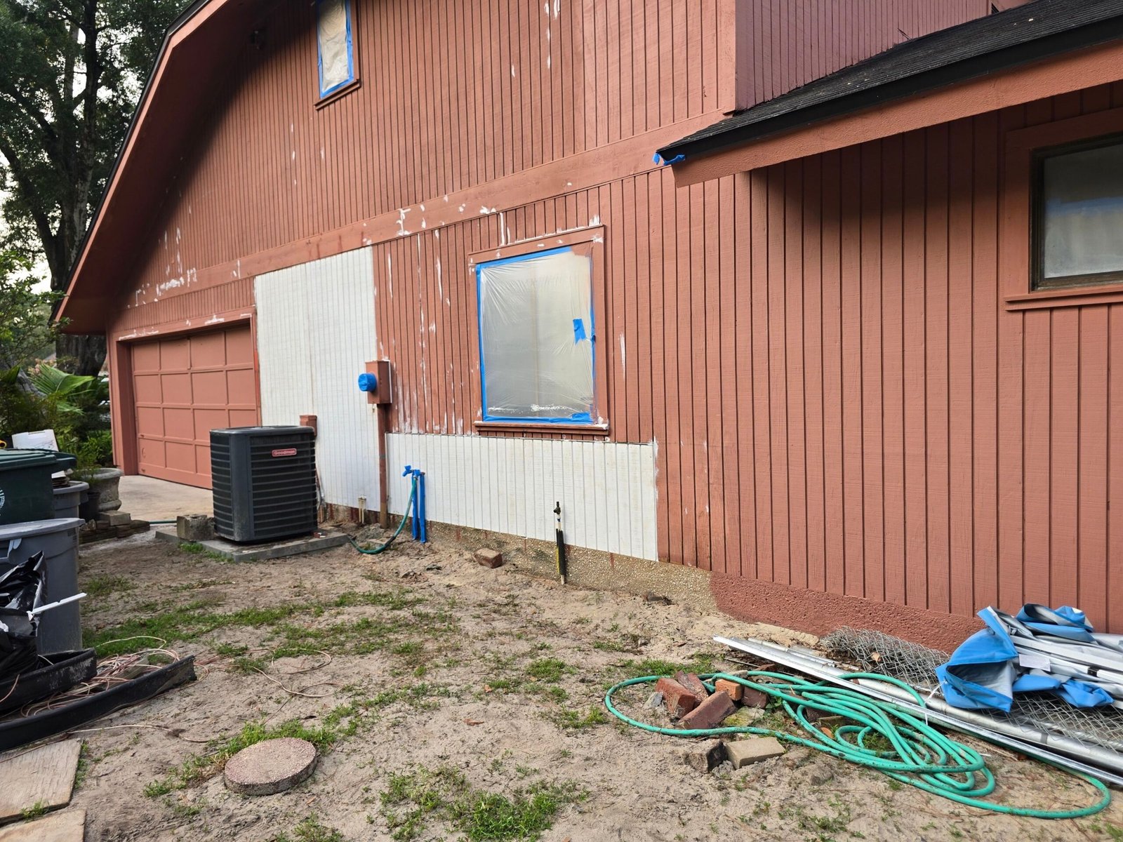 Completed T1-11 siding repairs on Secret Cove Jacksonville home — new replacement panels installed from ground level to mid-wall, adjacent existing siding visible above, surface ready for exterior painting