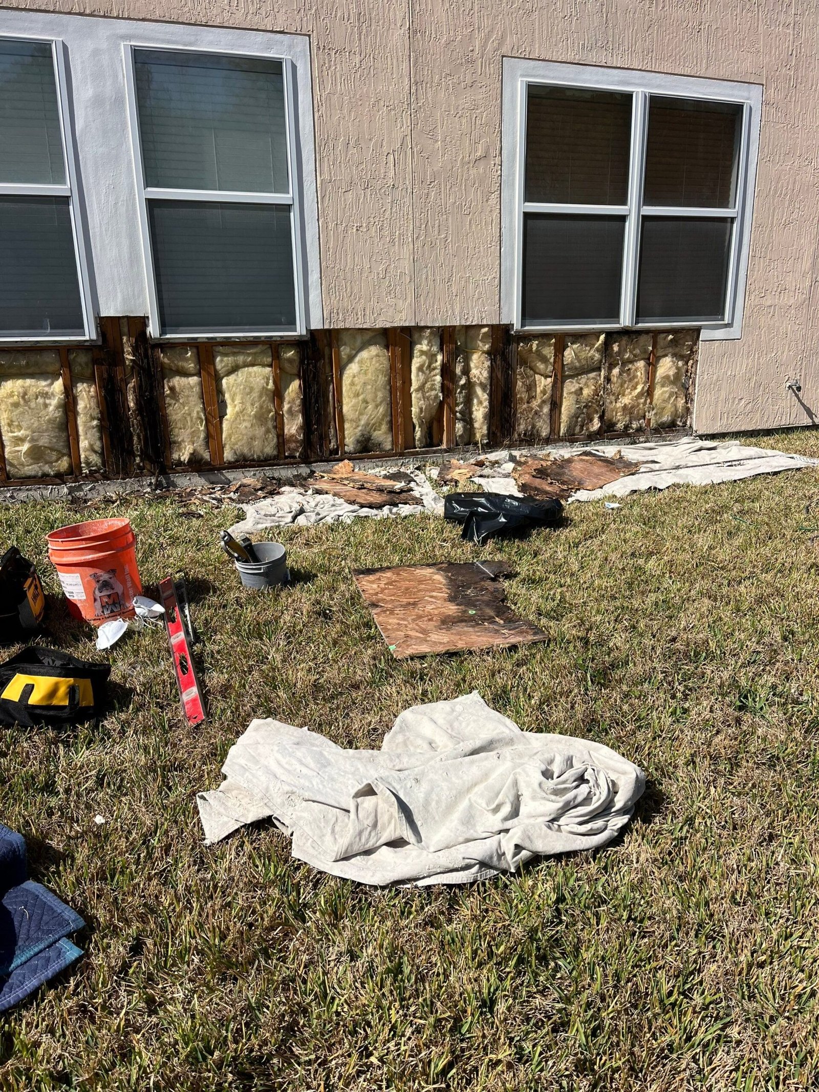 Loose stucco removed exposing damaged sheathing on an exterior wall